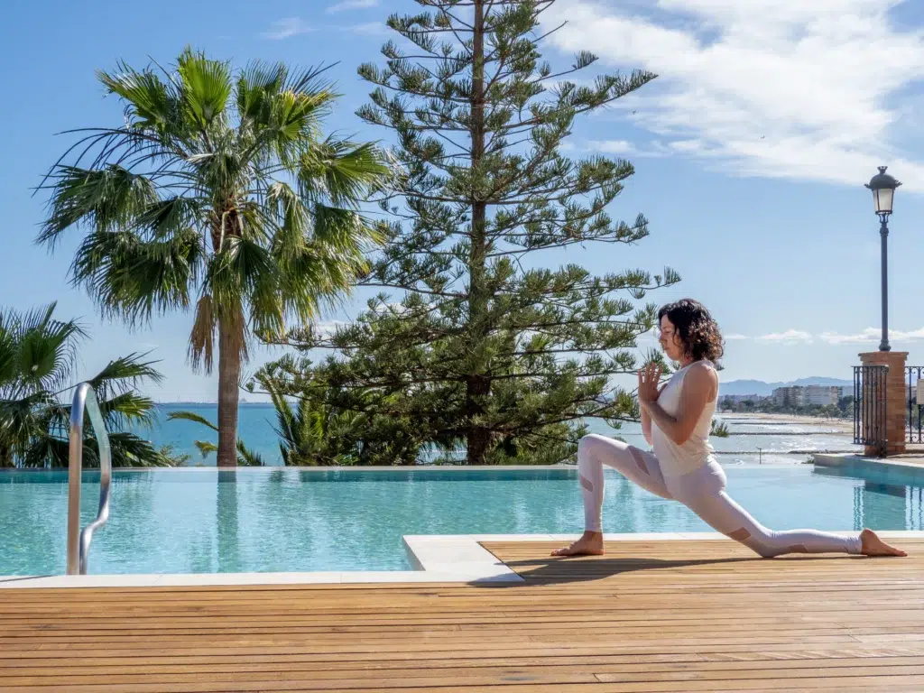 Femme pratiquant le yoga au bord de la piscine